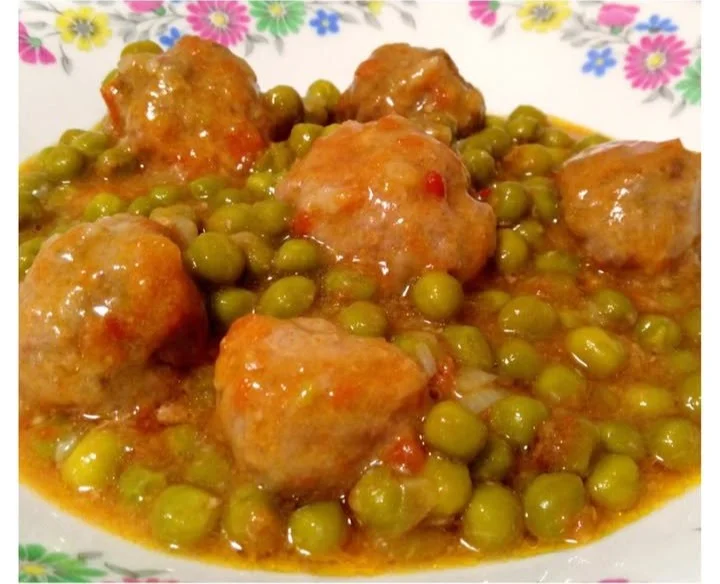 Albondigas de merluza en salsa con guisantes servidas en un plato