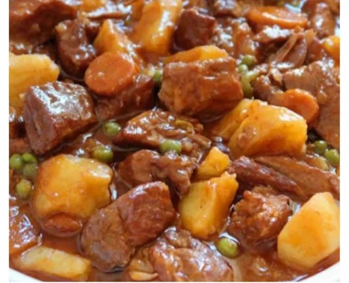 Estofado de cerdo cocinándose en una olla con verduras y especias.