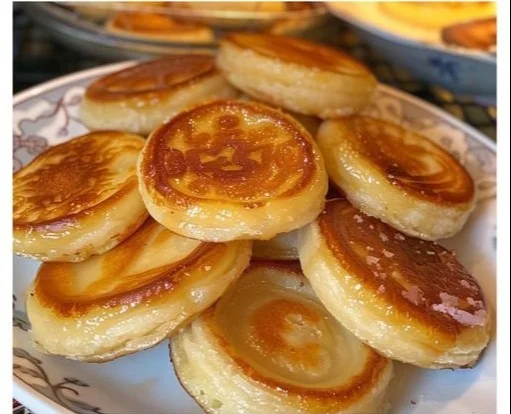 Mini pancakes esponjosos apilados en un plato con jarabe de arce
